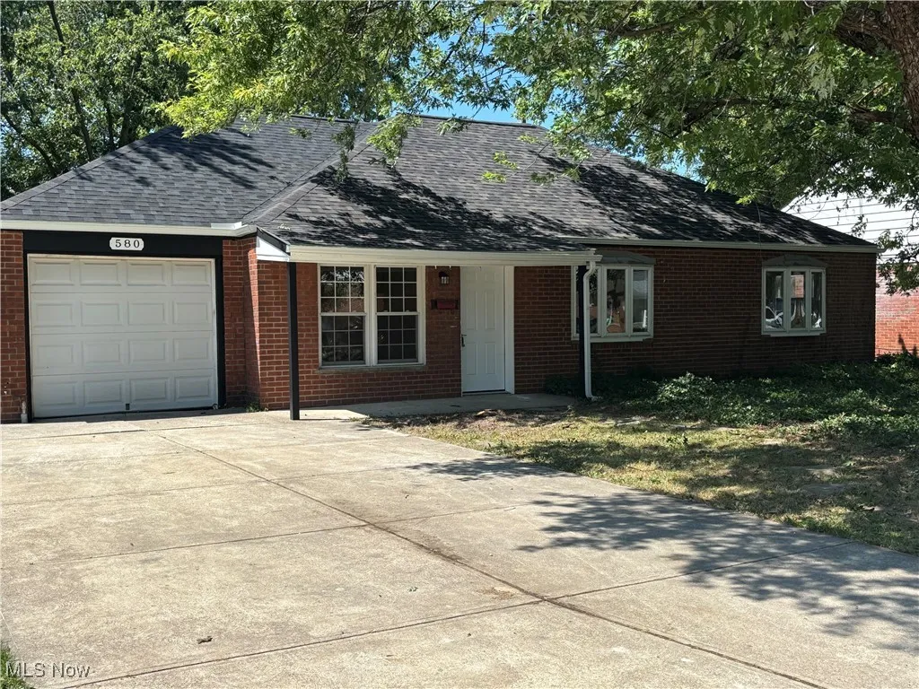 Single story home with brick siding, a shingled roof, concrete driveway, and a garage