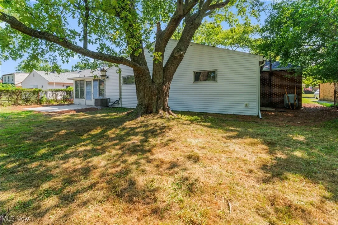 Rear view of property featuring a lawn, a patio area, and brick siding