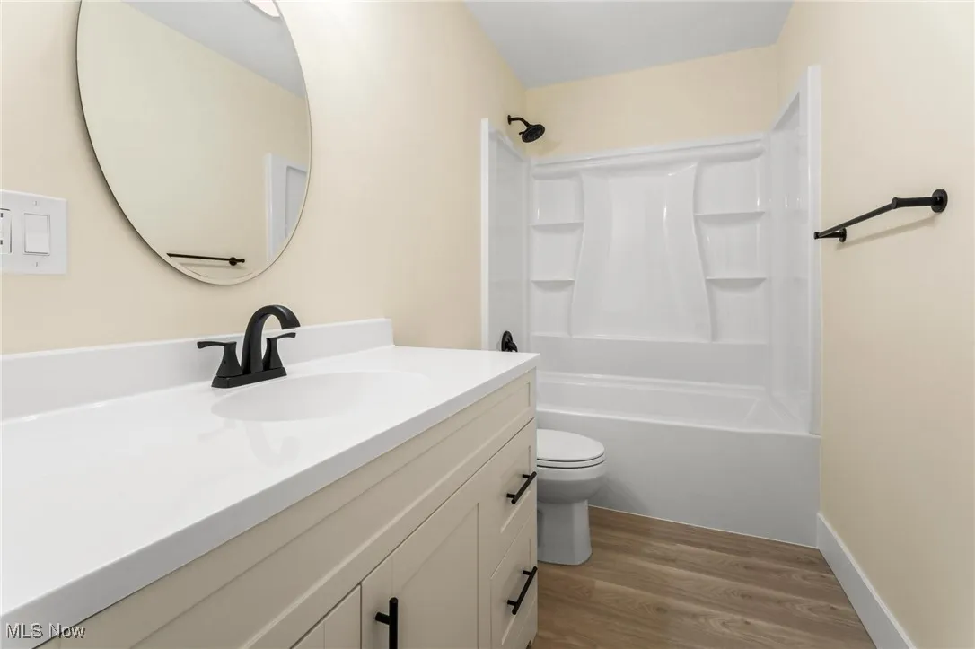Bathroom featuring wood finished floors, vanity, and  shower combination