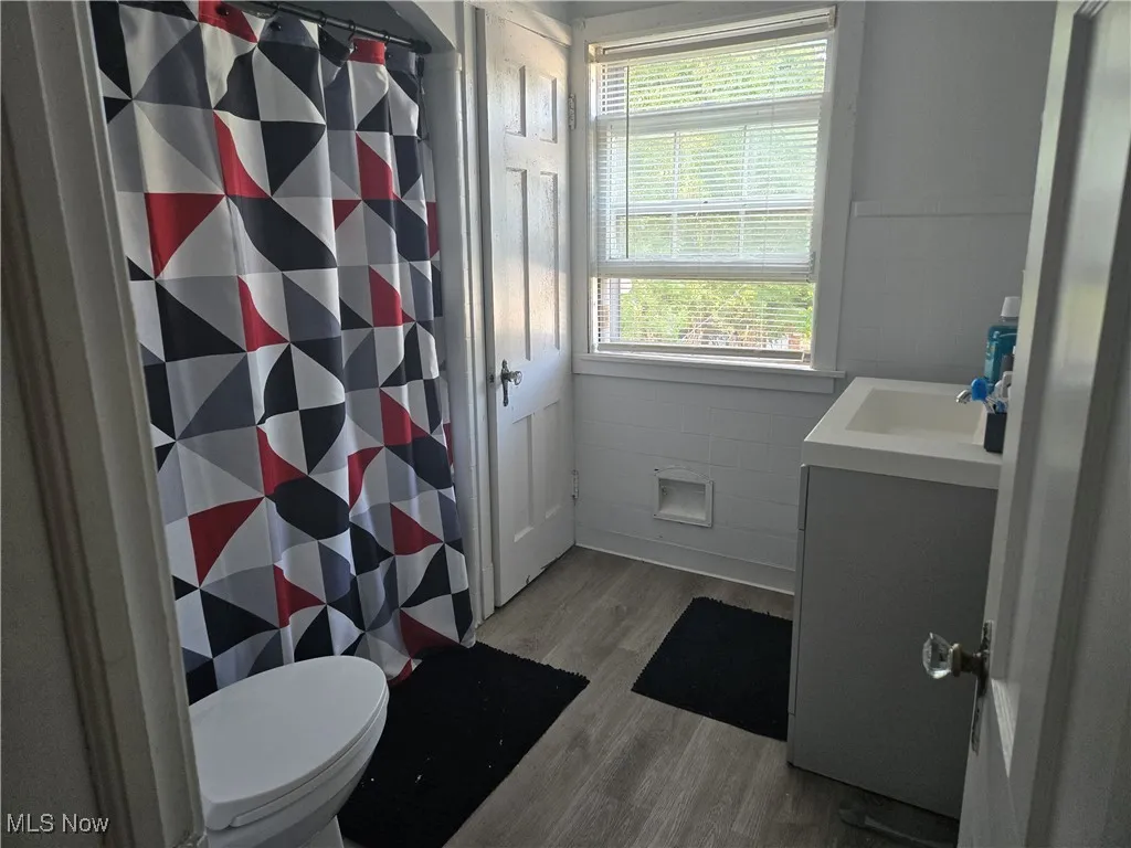 Bathroom with vanity, light wood finished floors, tile walls, and a stall shower