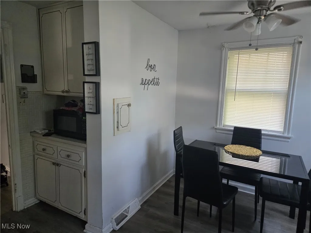 Dining area featuring dark wood-type flooring and ceiling fan