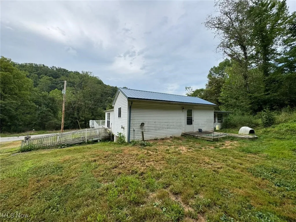 Rear view of house with a lawn, a metal roof, and a wooden deck