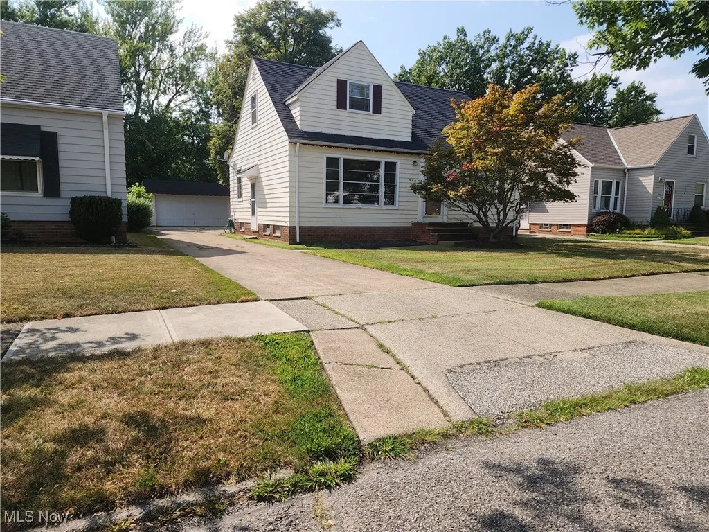 View of front of home with an outbuilding, a garage, a front yard, and a shingled roof
