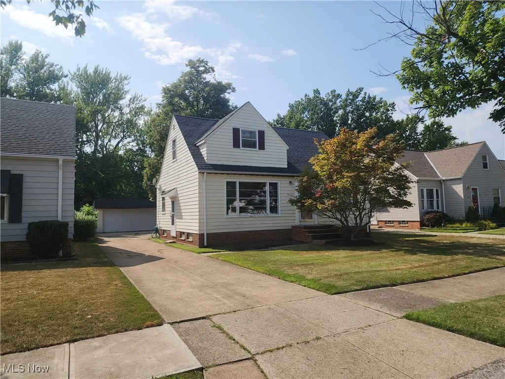 View of front of home featuring an outbuilding, a front lawn, a garage, and roof with shingles