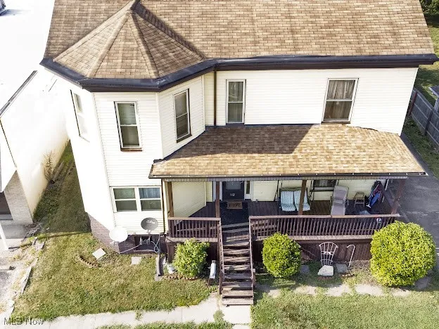 View of front of home featuring roof with shingles, stairway, and a porch
