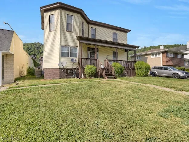 View of front of house featuring a porch, a front yard, and stairs