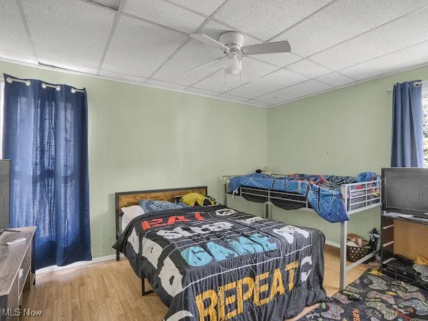 Bedroom with wood finished floors, a paneled ceiling, and a ceiling fan