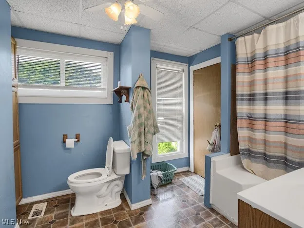 Bathroom featuring vanity, a ceiling fan, a drop ceiling, and shower / bathtub combination with curtain