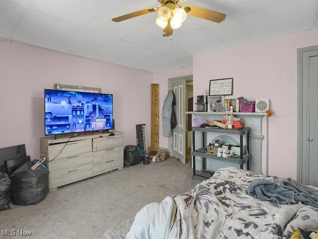 Carpeted bedroom with a ceiling fan