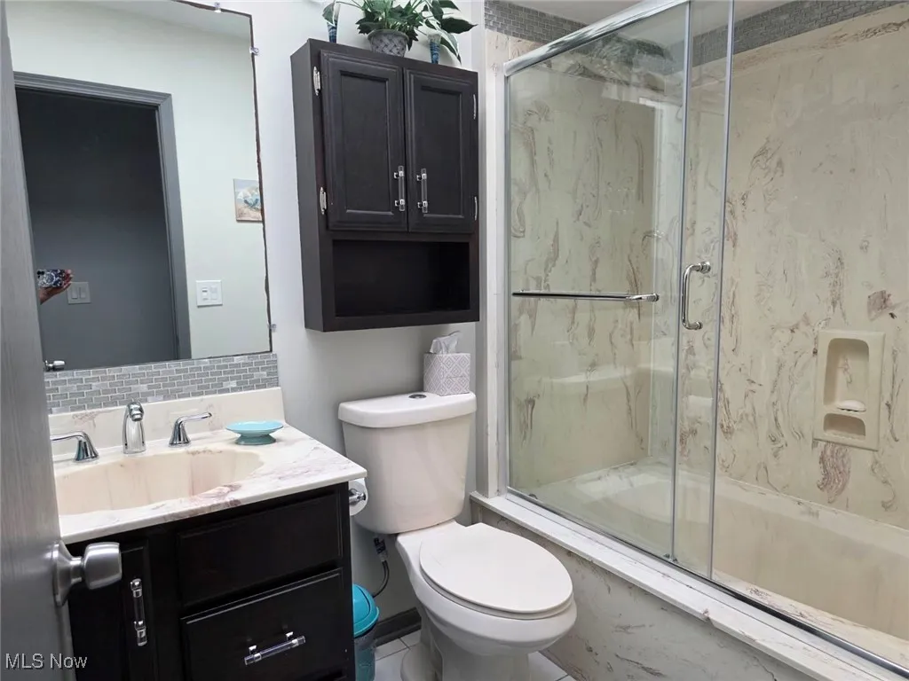 Bathroom featuring vanity and a marble finish shower
