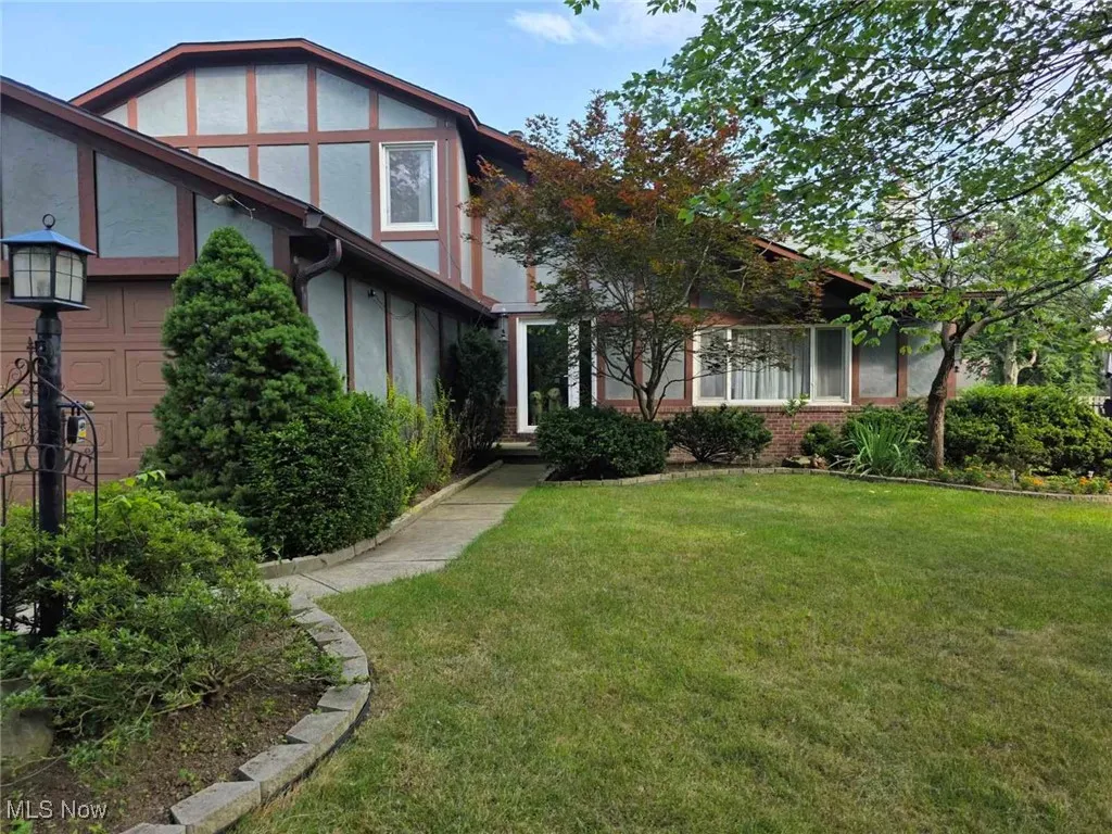 Tudor home with stucco siding, a front yard, a garage, and a sunroom