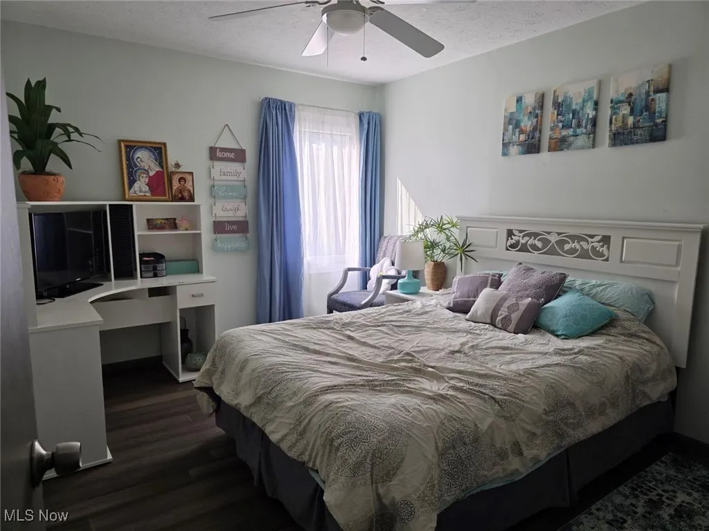 Bedroom with a textured ceiling, dark wood-style flooring, and ceiling fan