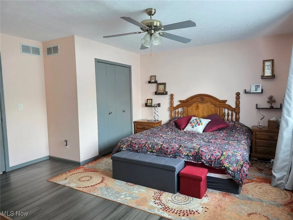 Bedroom with a closet, wood finished floors, ceiling fan, and a textured ceiling