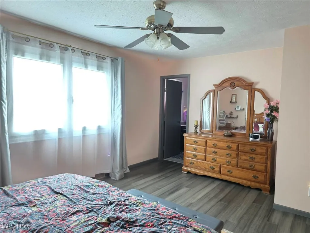 Bedroom featuring a textured ceiling, ceiling fan, and dark wood finished floors