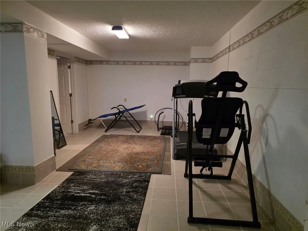 Exercise room with a textured ceiling and light tile patterned floors