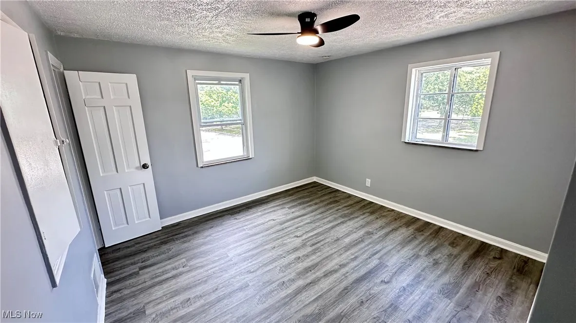 Spare room with wood finished floors, healthy amount of natural light, a textured ceiling, and ceiling fan