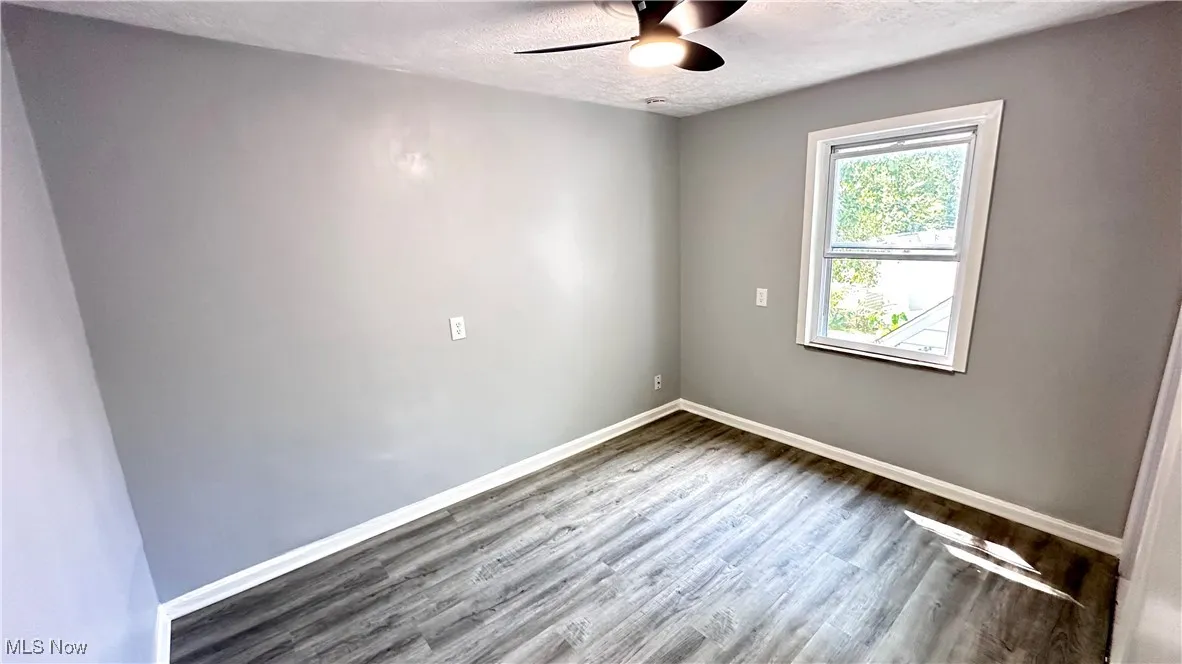Spare room featuring a textured ceiling, wood finished floors, and a ceiling fan