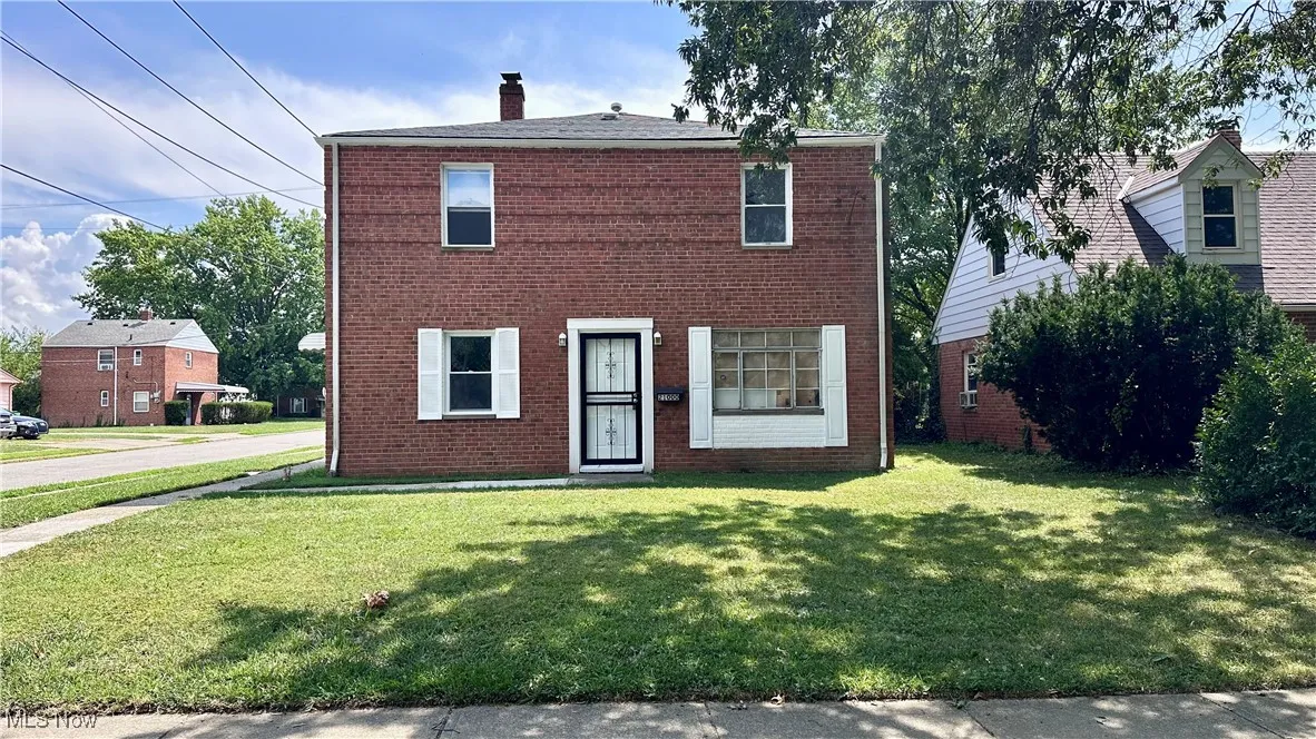 View of front of property with brick siding, a front lawn, and a chimney