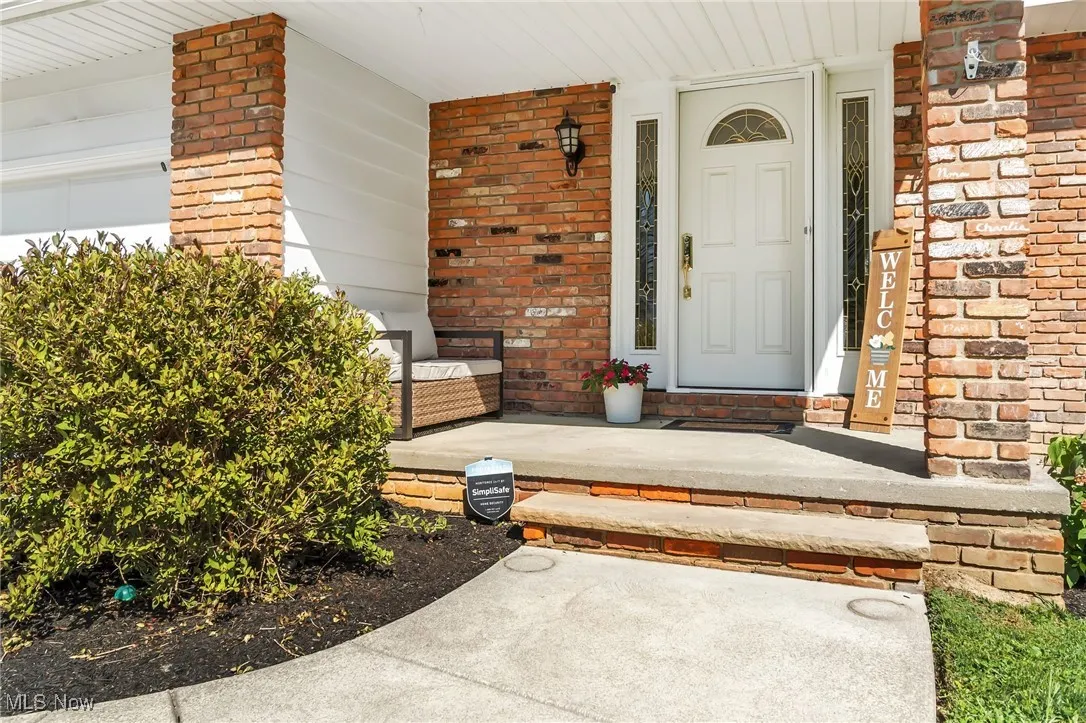 View of exterior entry with covered porch and brick siding