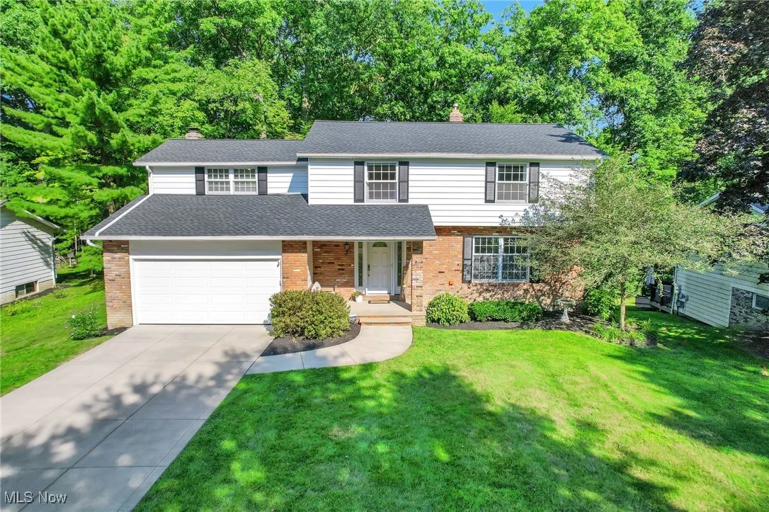 View of front of house with driveway, brick siding, a front lawn, and a chimney