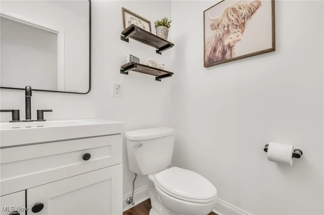 Half bathroom with vanity and dark wood-type flooring