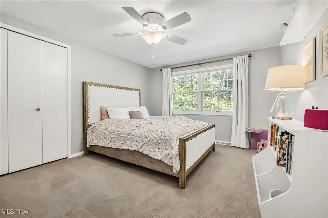 Carpeted bedroom with a ceiling fan and a closet