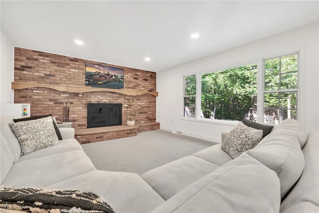 Living area featuring carpet floors, a fireplace, recessed lighting, and brick wall