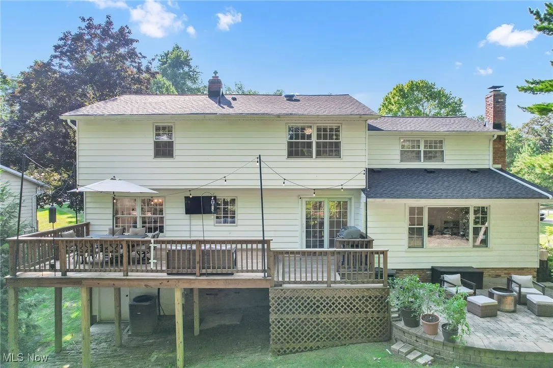 Back of property with a wooden deck, outdoor lounge area, a chimney, and a shingled roof