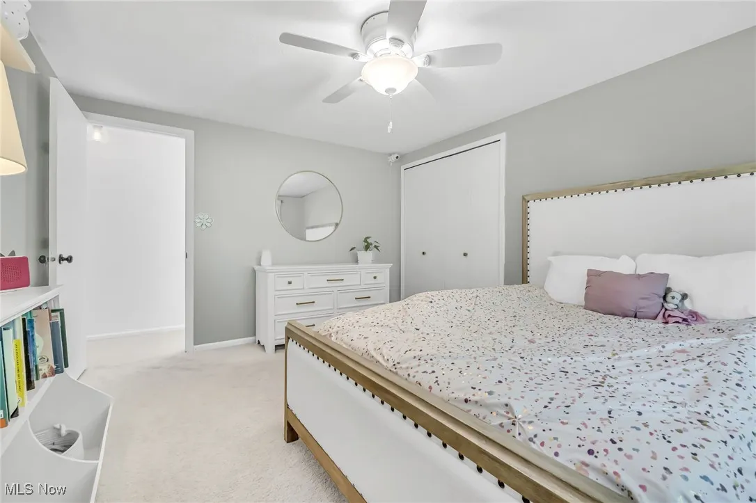 Bedroom featuring light carpet, a closet, and a ceiling fan