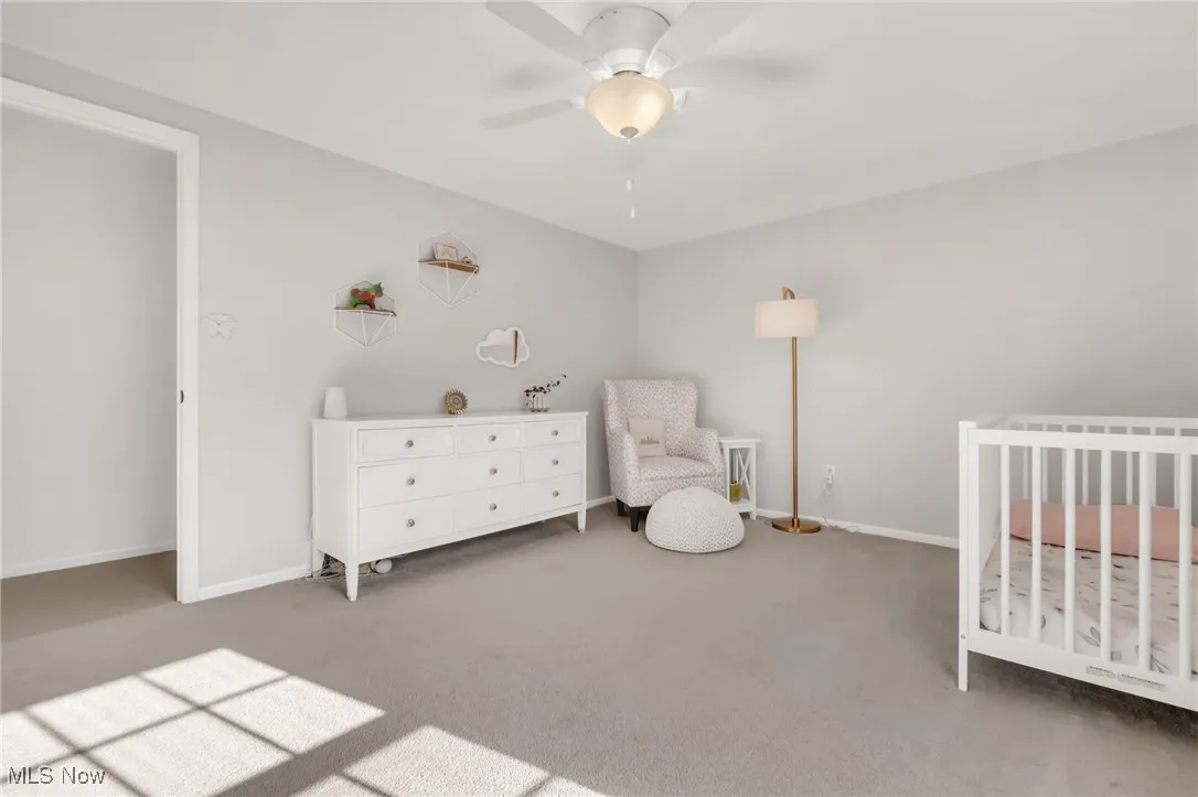 Bedroom featuring carpet, a crib, and a ceiling fan