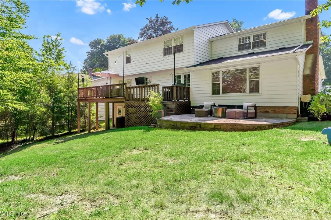 Back of house with a yard, a deck, a chimney, and a patio