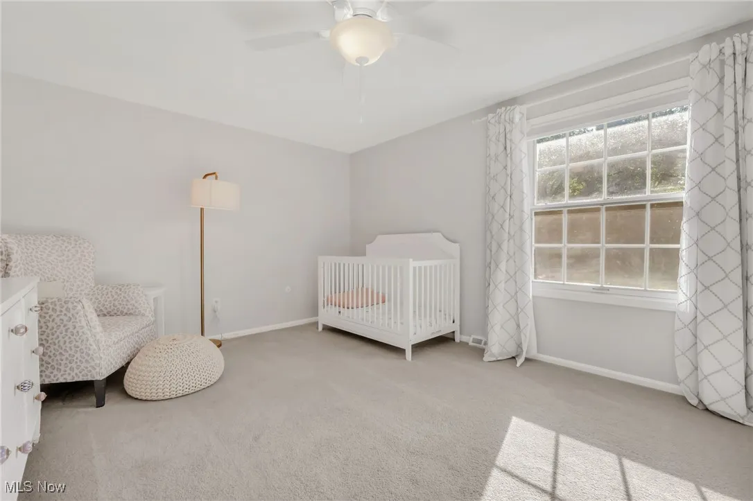 Bedroom featuring a crib, carpet, and a ceiling fan