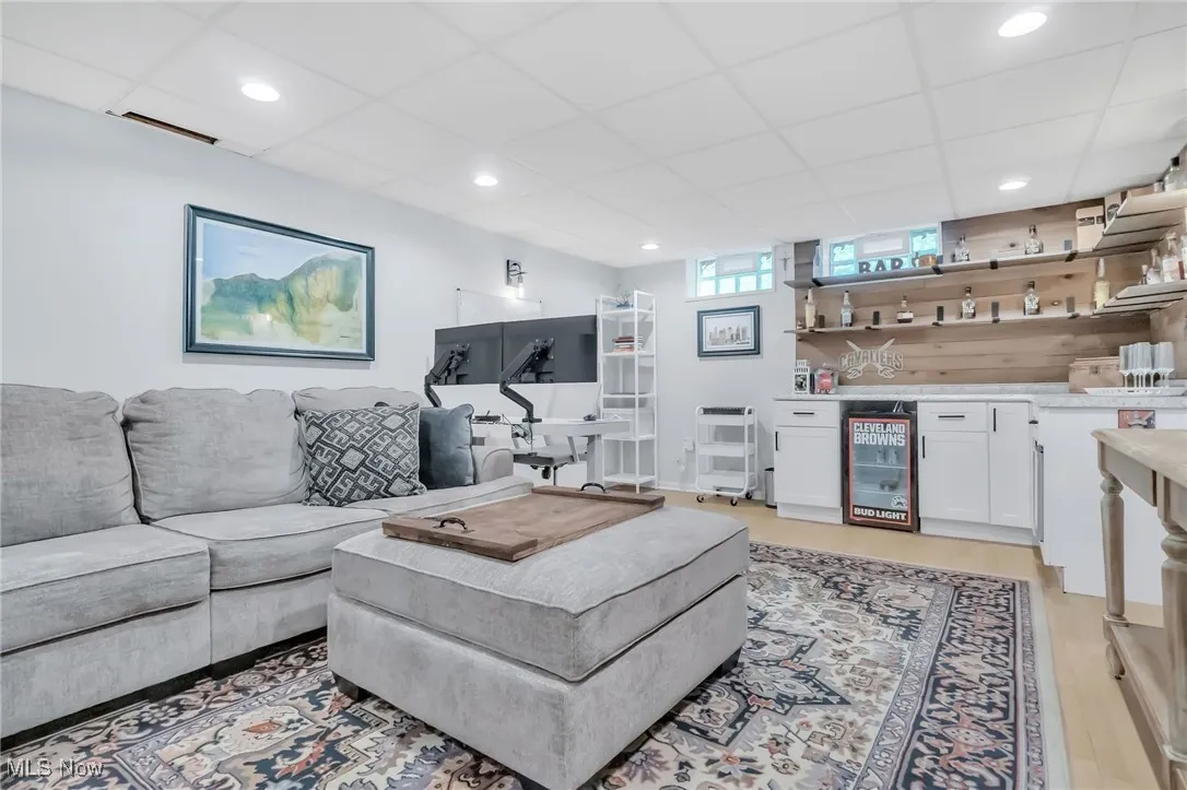 Living area with a bar, wine cooler, a drop ceiling, recessed lighting, and light wood-style flooring