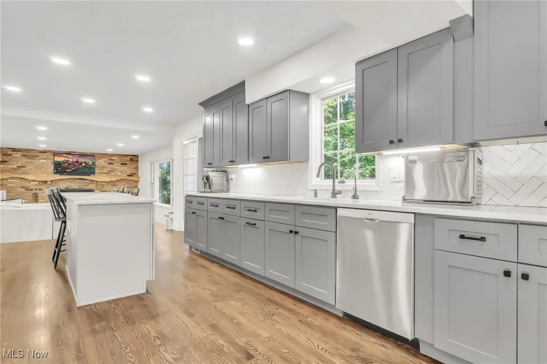 Kitchen featuring plenty of natural light, recessed lighting, gray cabinets, stainless steel dishwasher, and light wood-style flooring