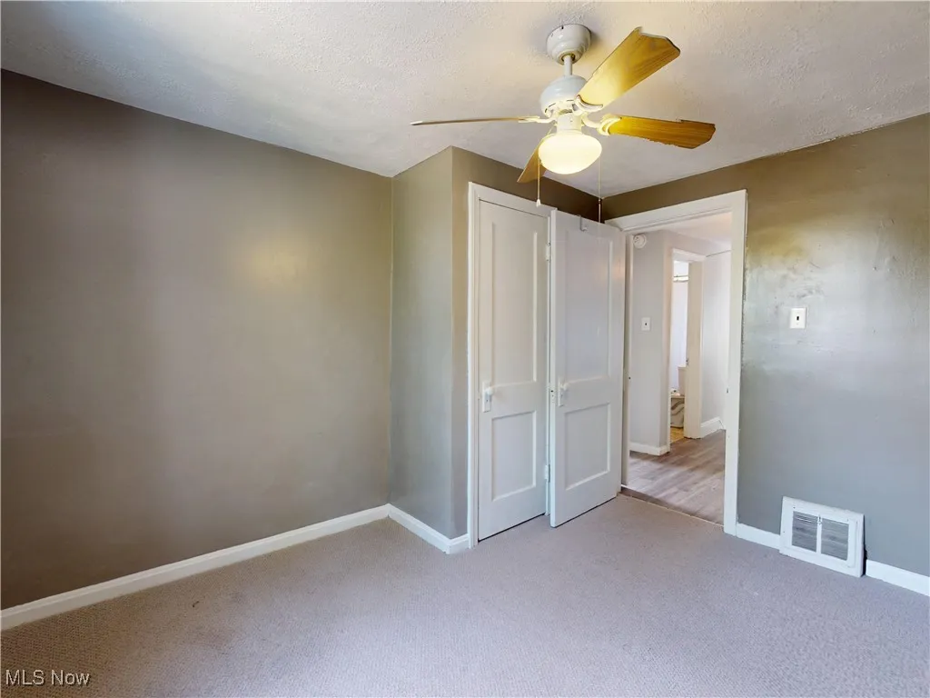 Unfurnished bedroom with light colored carpet, a textured ceiling, a ceiling fan, and a closet