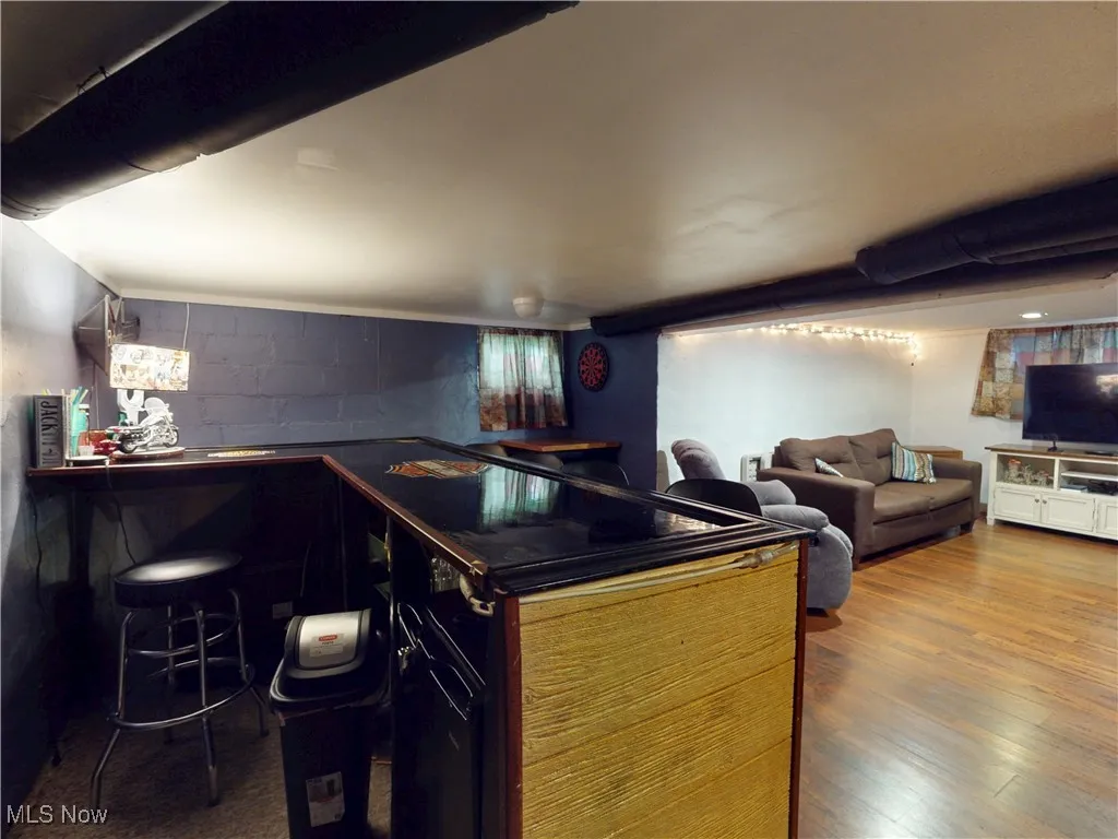 Indoor dry bar with dark countertops, dark wood-style flooring, and concrete block wall