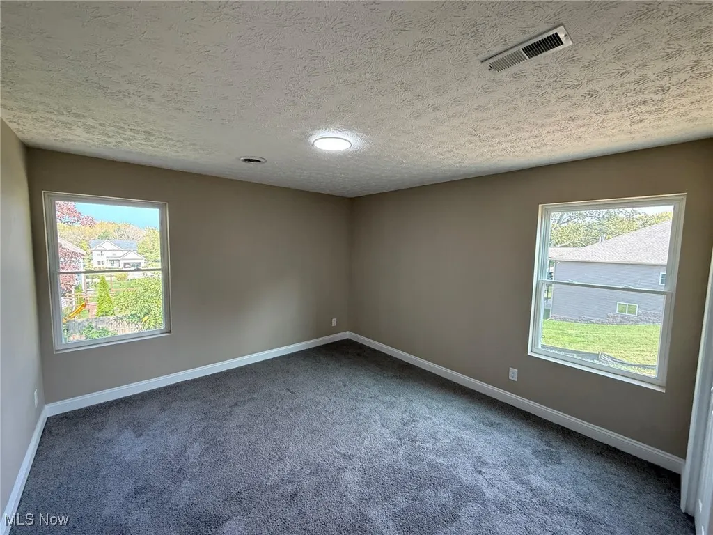 Carpeted spare room with a textured ceiling and recessed lighting