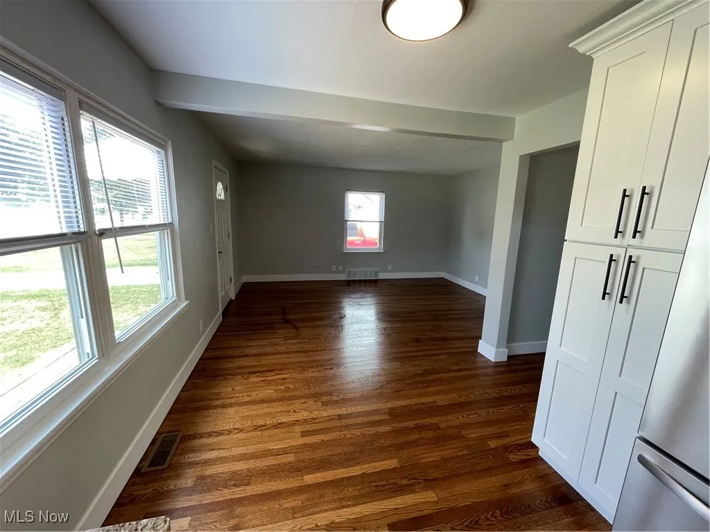 Unfurnished room with dark wood-style flooring and baseboards