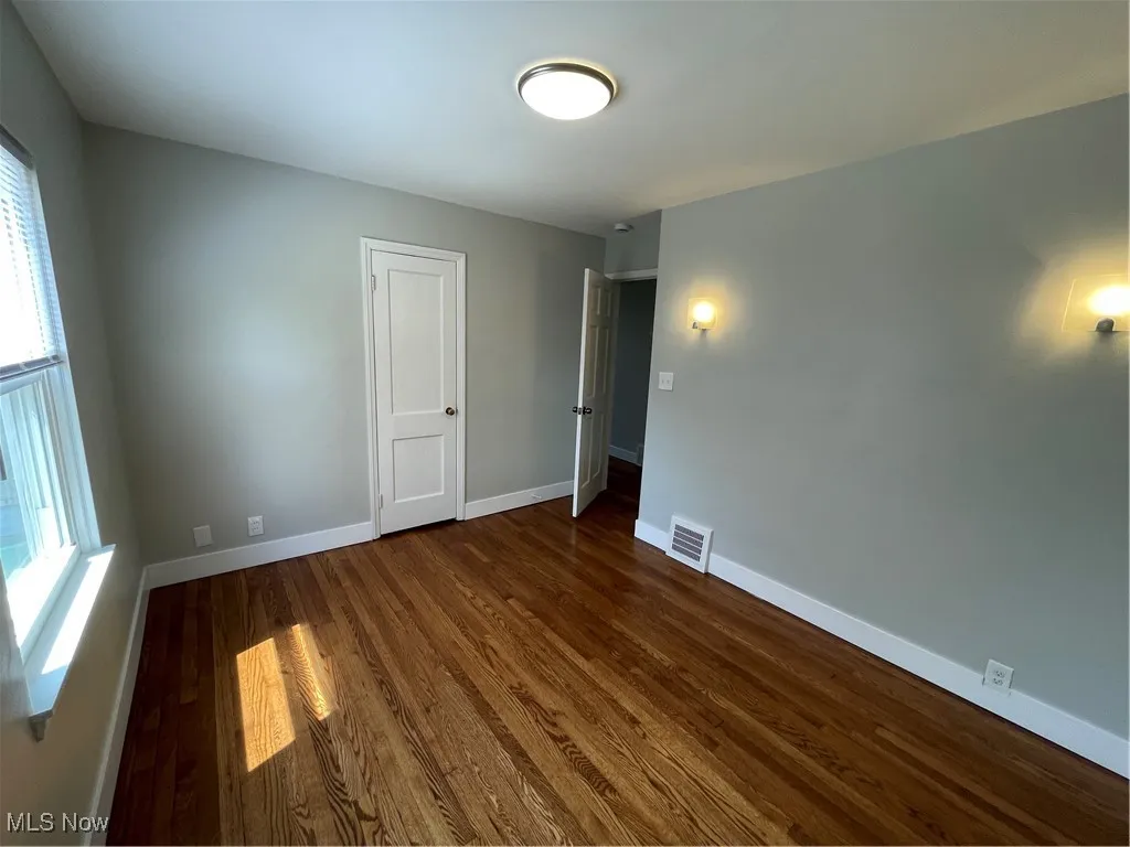 Unfurnished room featuring baseboards and dark wood-type flooring