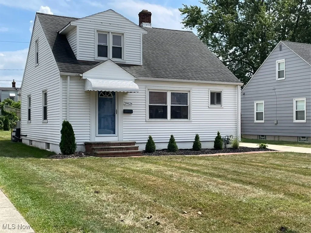 View of front of property with roof with shingles, a chimney, a front yard, and entry steps