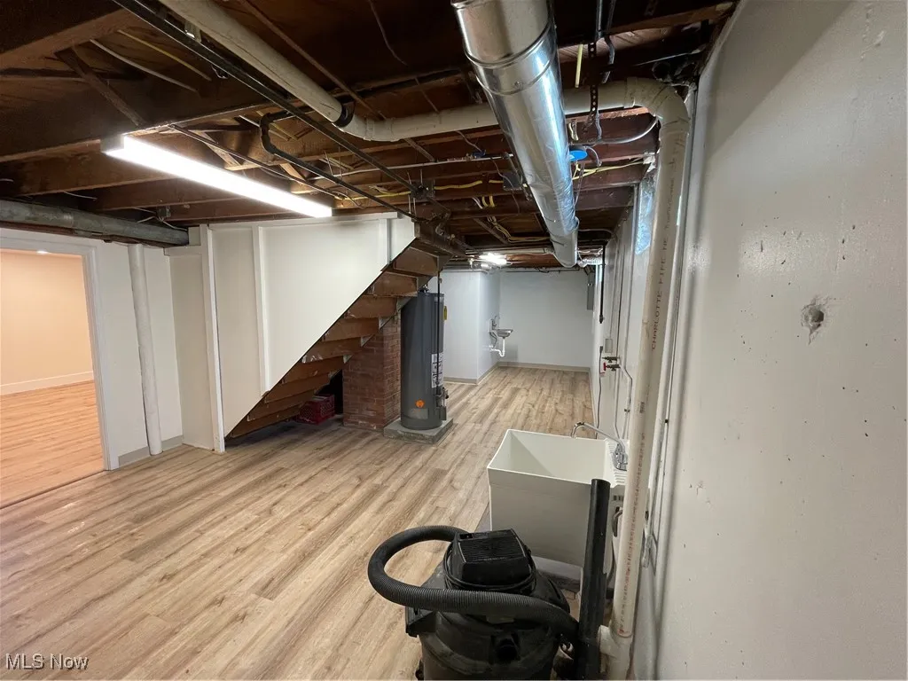 Unfinished below grade area featuring light wood finished floors and water heater