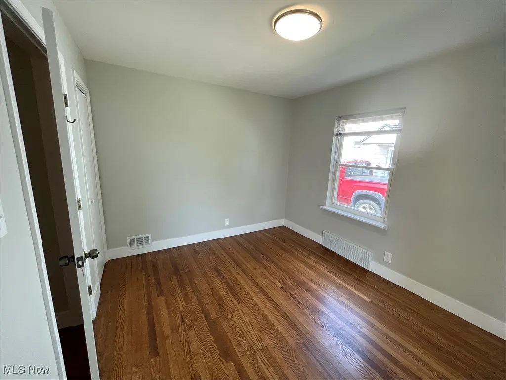 Empty room featuring dark wood-type flooring and baseboards
