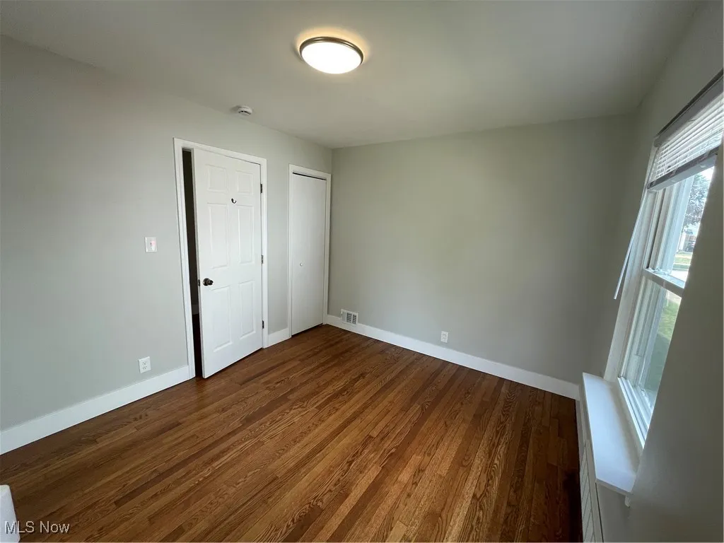 Unfurnished bedroom with dark wood-style floors, a closet, and a baseboard heating unit