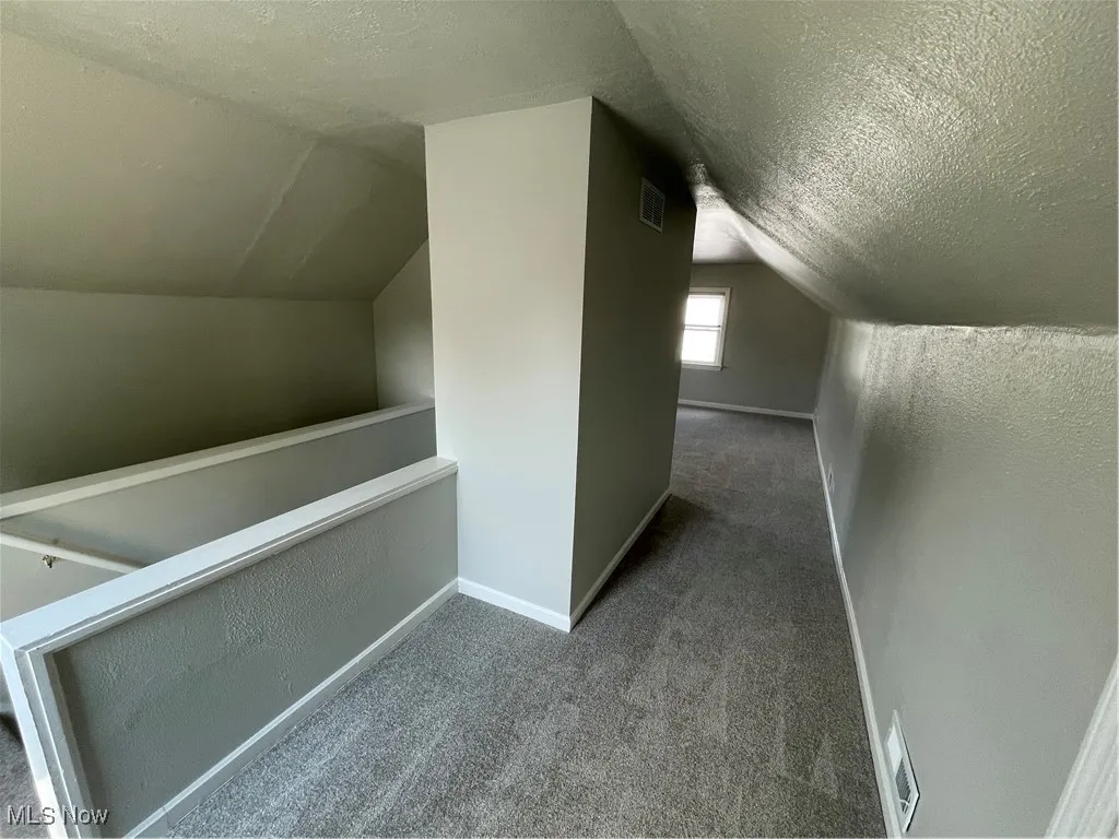 Bedroom space featuring carpet, a textured ceiling, lofted ceiling, and a textured wall