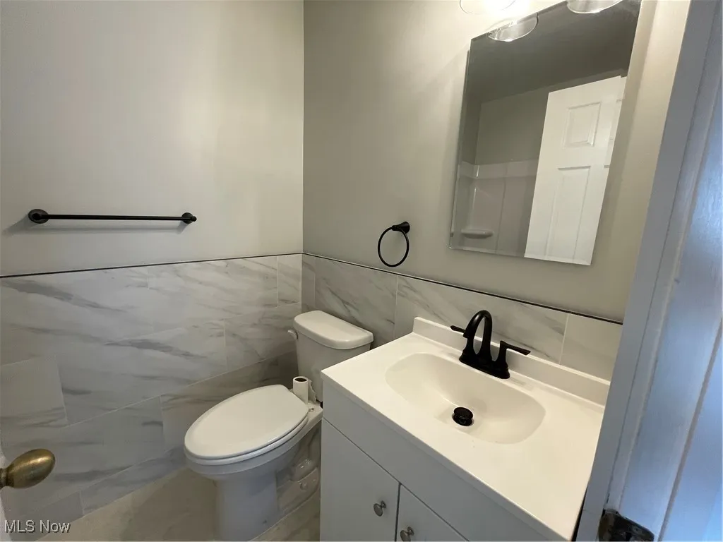 Bathroom with tile walls, vanity, and a wainscoted wall