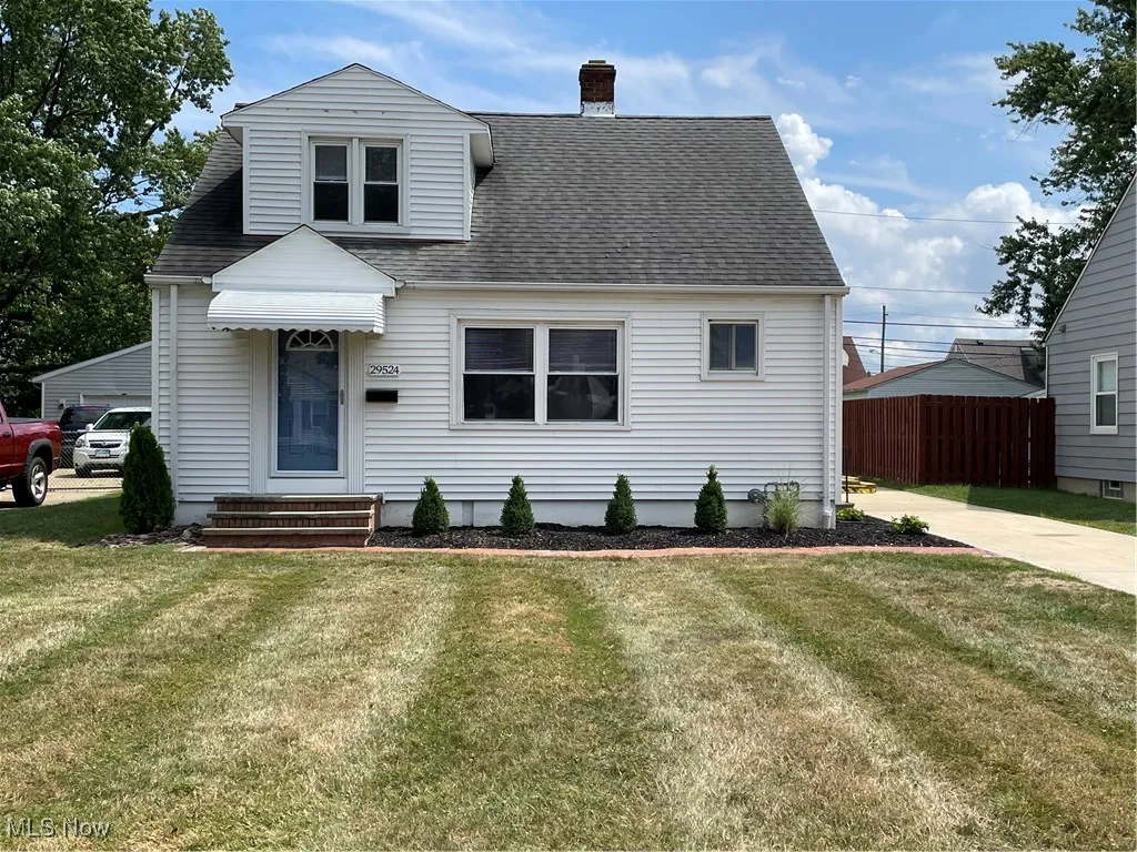 View of front of house featuring a front lawn, a shingled roof, and a chimney