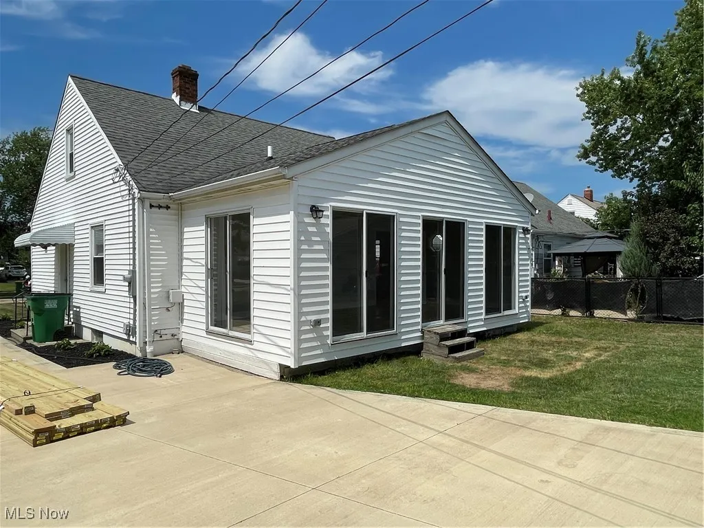Rear view of house featuring a chimney and roof with shingles