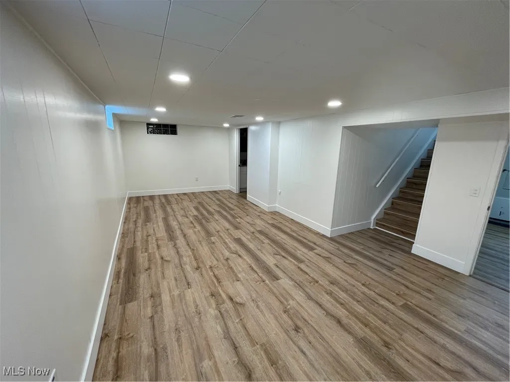 Finished below grade area featuring light wood-type flooring, stairs, and recessed lighting