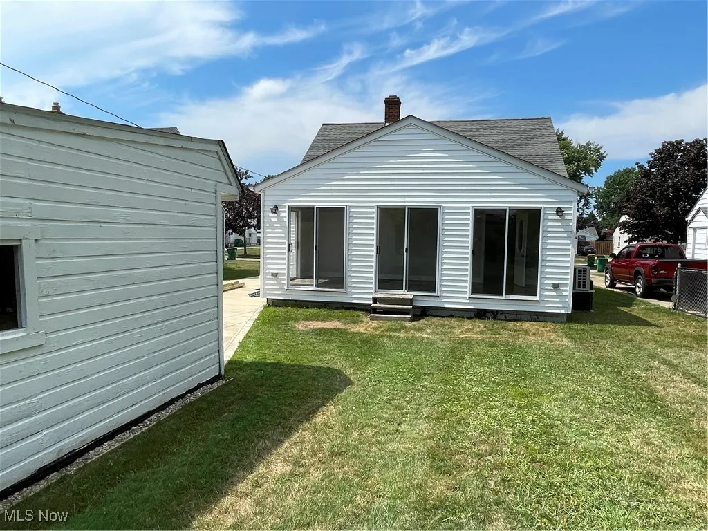 Rear view of house with a yard, roof with shingles, and a chimney