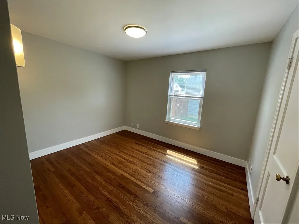 Empty room featuring baseboards and dark wood-style floors